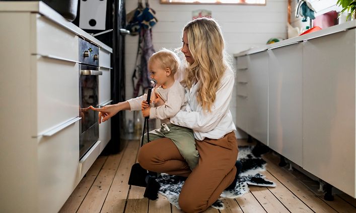 Kvinne og baby som ser inn i stekeovnen