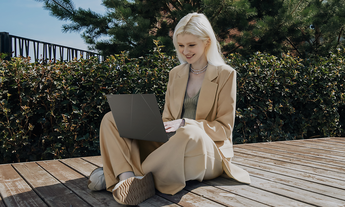 Woman sitting outside on a deck, working with ASUS Zenbook S 16